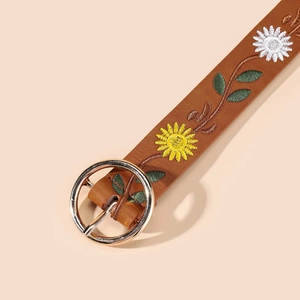 Detailed view of floral embroidery on brown leather belt with a round metal buckle
