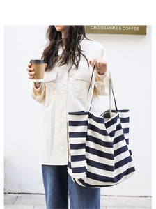 Close-up of a high-capacity navy blue and white striped canvas tote bag in a cafe setting