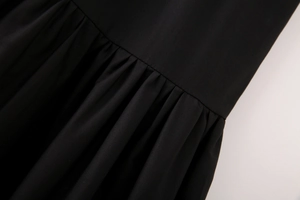 Détail du plissage sur le tissu en coton noir et des coutures fines de la robe midi