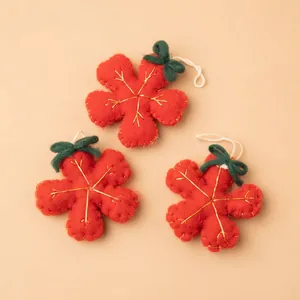 Three red wool felt snowflake ornaments with green bows and gold embroidery details