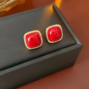 Macro shot of red gemstone earrings with gold plating and cubic zirconia on black box