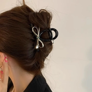 Elegant large metal bow hair claw clip in black and silver on model's hair