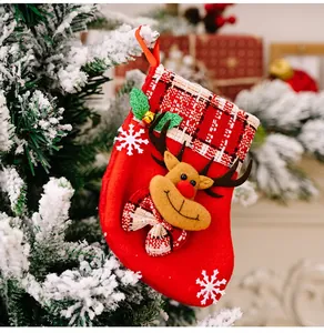 Détail d'une chaussette de Noël rouge avec renne en peluche sur une branche enneigée
