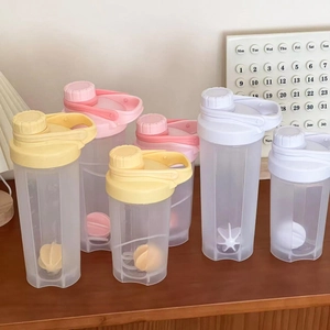 Frosted plastic protein shaker bottles with scales and mixing balls on a wooden table