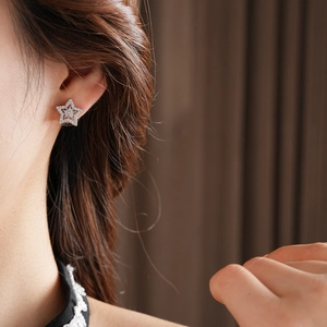 Close-up of star-shaped silver stud earring with cubic zirconia on model's ear