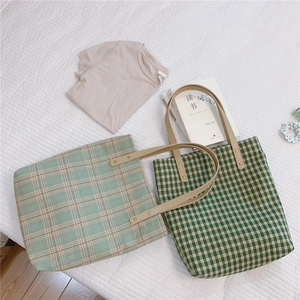 Détail de sacs fourre-tout à carreaux verts avec anses en cuir et rivets en métal