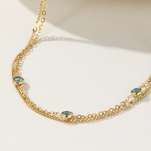 Bracciale a doppio strato dorato con tre zirconi blu rotondi in uno stile minimalista