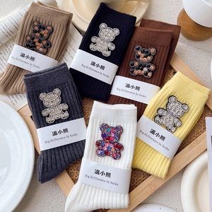Six colors of ribbed crew socks with rhinestone bear patches in a wooden tray