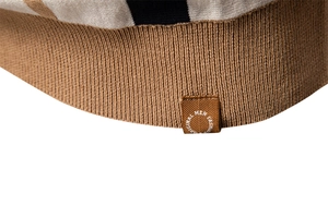 Macro detail of men's knitted polo shirt hem with brown stripe pattern and brand woven label