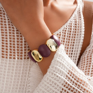 Gros plan d'un large bracelet en acrylique avec maillons dorés et accents violets