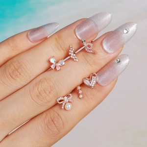 Set de pendientes de oro rosa con colgantes de mariposa y corazón mostrados en la mano