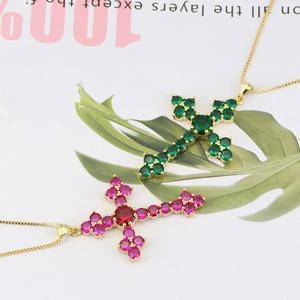 Close-up of gold cross necklaces with emerald green and rose red sparkling crystals