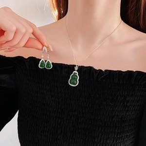 Close-up of model wearing green gemstone gourd pendant necklace and matching earrings