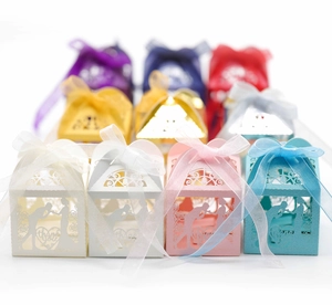 Close-up of laser-cut wedding favor boxes with hearts and ribbons in various colors