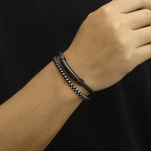 Detail of a double-layer black woven leather bracelet with polished steel tube on wrist