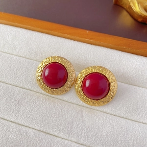 Macro detail of vintage gold stud earrings with a large red cabochon and embossed texture