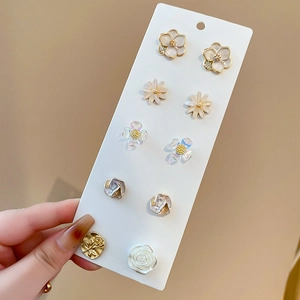 Detailed close-up of a 10-piece floral stud earring set with gold finish and pearls
