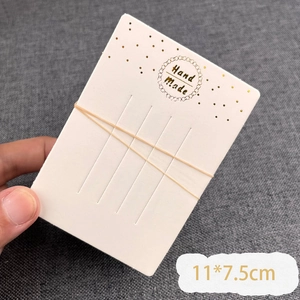 Close-up of ivory jewelry display card with gold Hand Made text and fixed straps