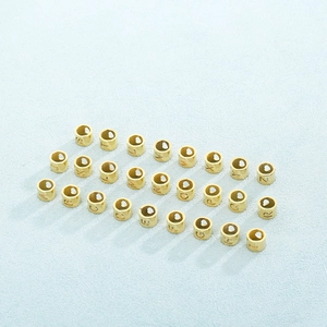 Close-up of golden titanium steel alphabet cylindrical beads for jewelry making