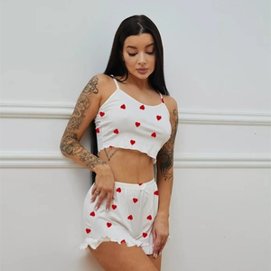 Close-up of white pajama set with red heart print featuring ruffle hem and bow detail