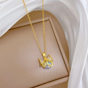 Close-up of golden bow necklace with pearl center and pavé crystals on silk