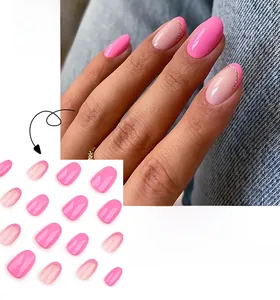 Detail of short round rose pink fake nails with golden glitter frame on denim background