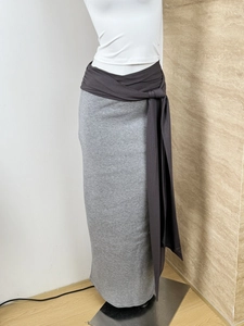 Detail of grey knitted maxi skirt featuring a contrast dark brown crossover tie waist design