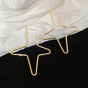 Macro detail of large gold geometric star earrings with minimalist sleek metal finish
