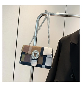 Detailed shot of crossbody bag featuring geometric patchwork patterns and rhinestone buckle