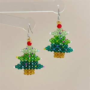 Detail of handmade beaded Christmas tree earrings with colorful crystals and red bow hooks