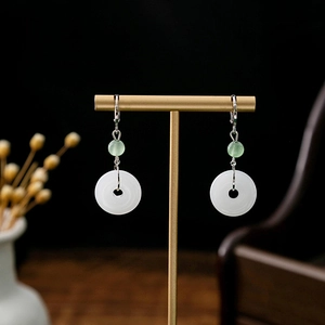 Detail of traditional Chinese earrings with white jade-like stones and green beads on a stand