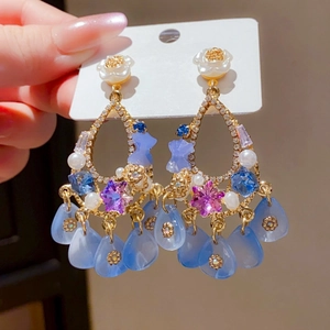 Detail of vintage gold tassel earrings with white flowers and blue crystal teardrops