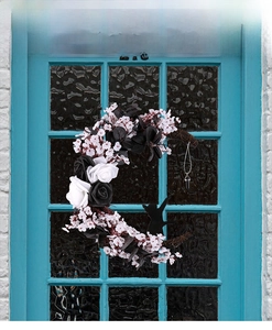 Detail of crescent moon wreath with black and white roses and a cat silhouette on a blue door