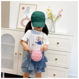 Pink quilted round chain bag for kids with heart pattern stitching shown on child model