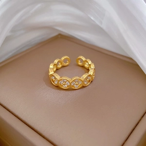 Adjustable gold clover ring with pavé cubic zirconia on jewelry box background