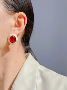 Macro shot of vintage style round red gem earrings with cream enamel and gold details