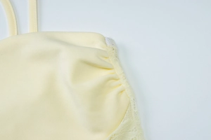 Close-up of the high-quality lace stitching and knitted fabric texture on yellow dress