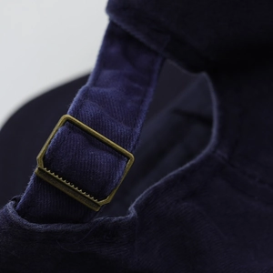 Detailed macro shot of the adjustable metal buckle on dark blue cotton baseball cap