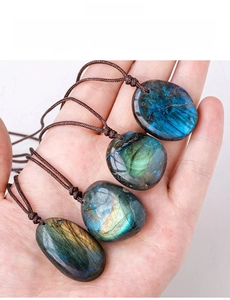 Close-up of four polished natural labradorite pendants with vibrant blue flashes on hand