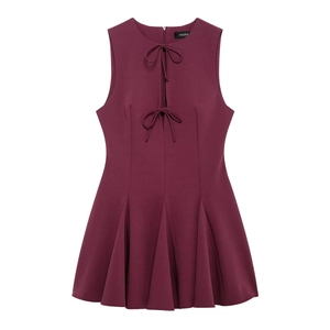 Detail of burgundy sleeveless dress featuring front bow ties and pleated skirt design