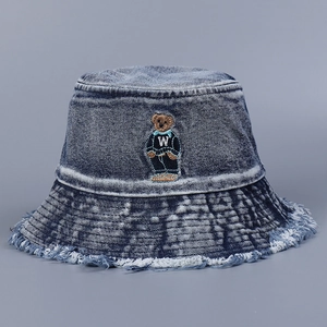 Detailed embroidery of a bear on a navy blue washed denim bucket hat with frayed edges