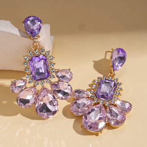 Detailed shot of vintage gold earrings with purple emerald-cut gems and rhinestones