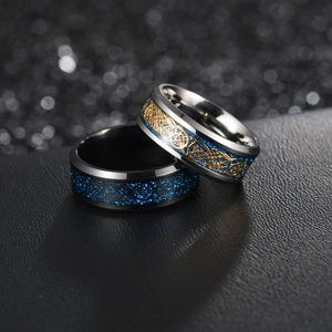 Macro shot of silver and black stainless steel rings with blue inlay and golden dragon pattern