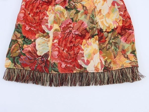 Detail of vintage oil painting dress featuring colorful floral jacquard and fringe hem