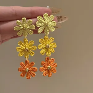 Detailed view of woven daisy drop earrings with three-tier yellow gradient flower design