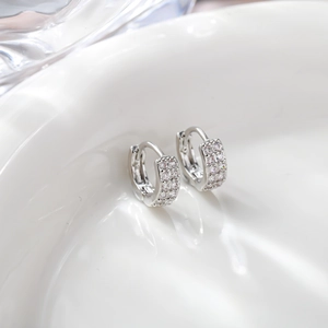 Macro shot of silver hoop earrings with triple-row pavé cubic zirconia on white tray