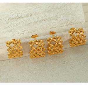 Detailed view of four hollow woven gold bead stud earrings on a textured lace background