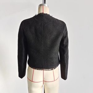Detailansicht der Rückseite einer schwarzen Tweed-Jacke mit Fransenbesatz und kurzem Schnitt