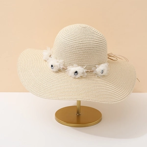 Gros plan d'un chapeau de paille beige avec fleurs blanches et un détail de nœud fin