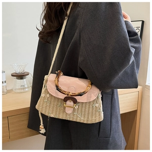 Detail shot of straw woven handbag with pink flap, floral embroidery and bamboo handle